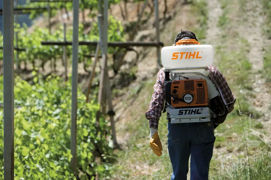 Operador aplicando defensivo em pomar com pulverizador Stihl SR 420