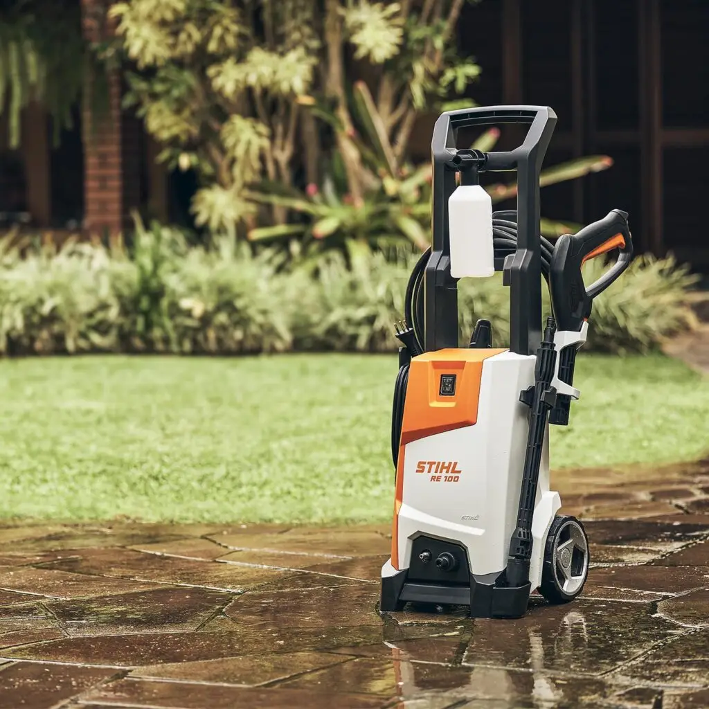 Lavadora de alta pressão Stihl RE 100 em jardim residencial, indicada para limpeza de áreas externas com mais potência e praticidade.