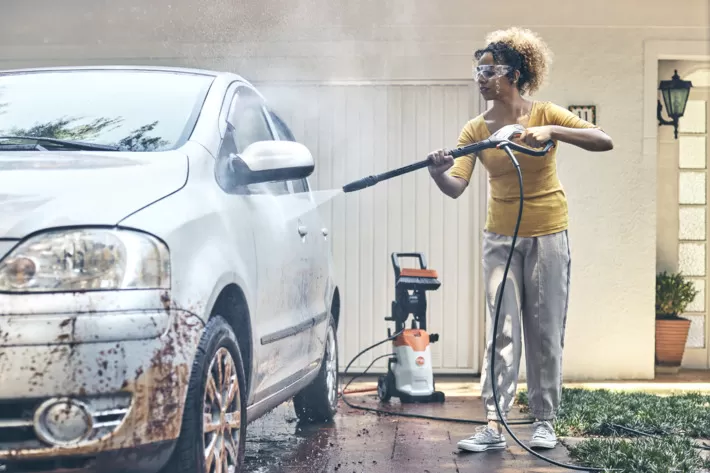 Lavadora de alta pressão Stihl RE 90 Plus sendo usada para lavar carro, indicada para limpeza automotiva e uso doméstico frequente.